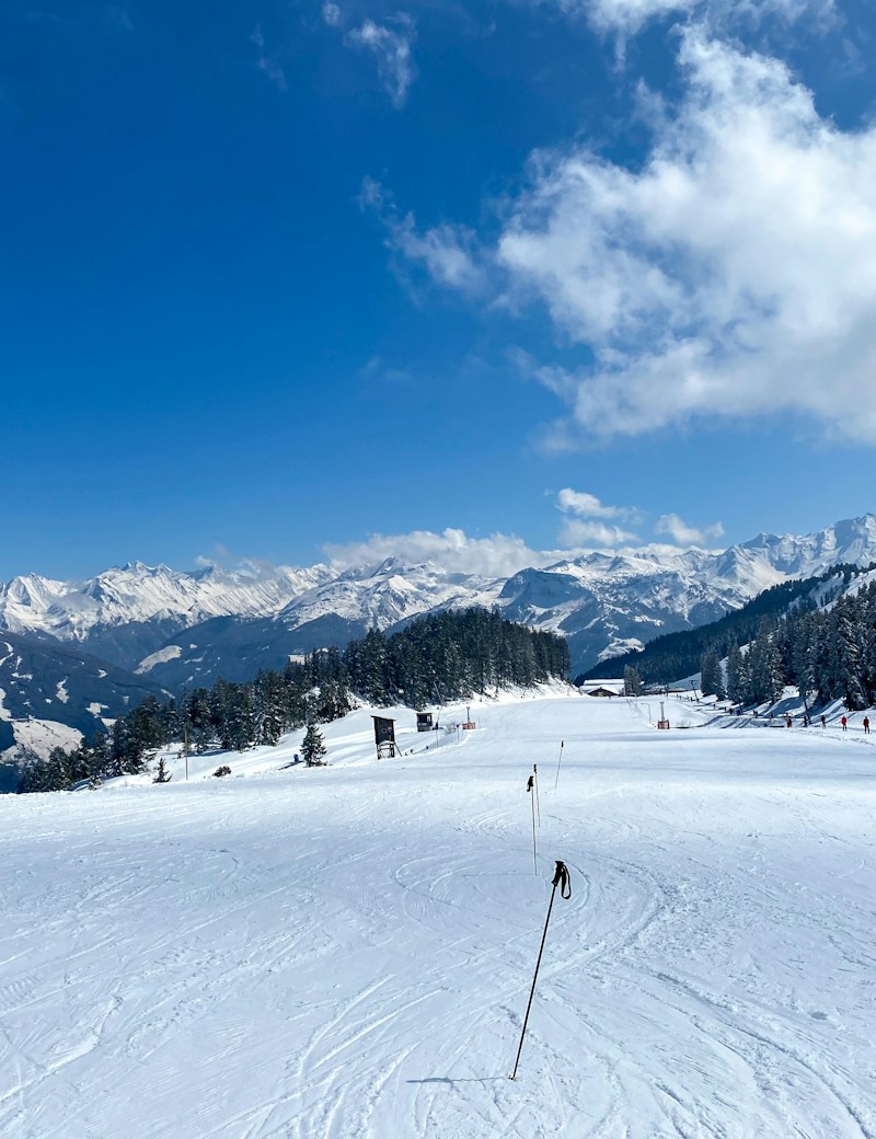 Sunlit, snow-covered mountains above a quiet ski slope